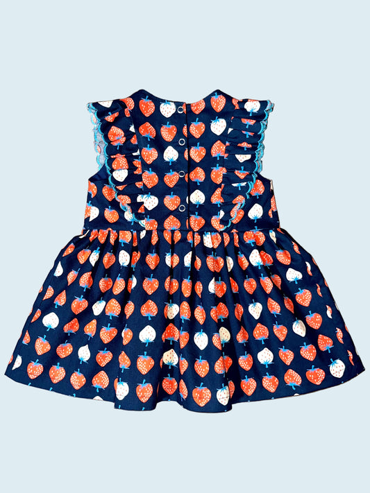 Children's dress with red and white strawberry pattern on navy background.