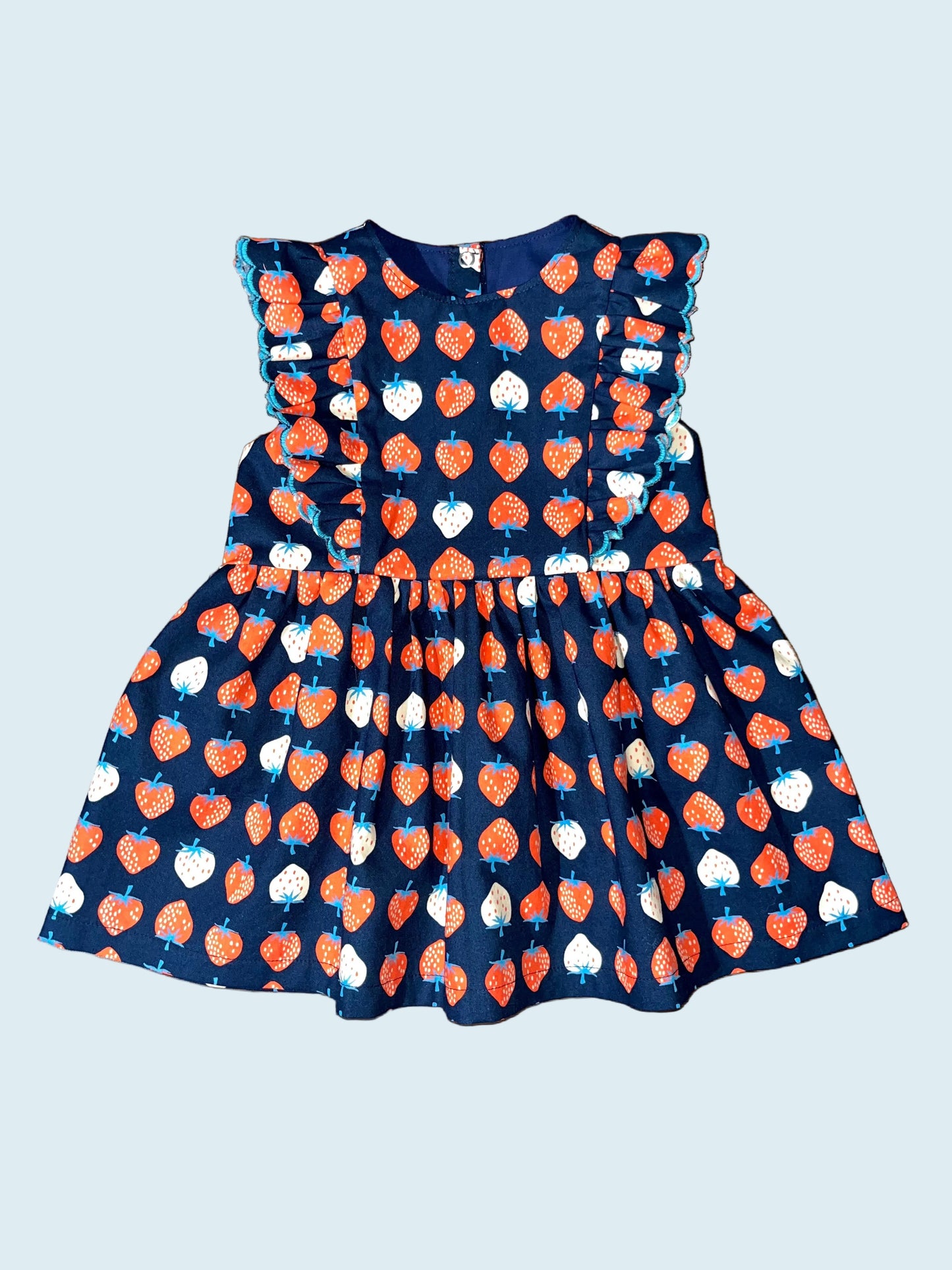 Children's dress with red and white strawberry pattern on navy background. 
