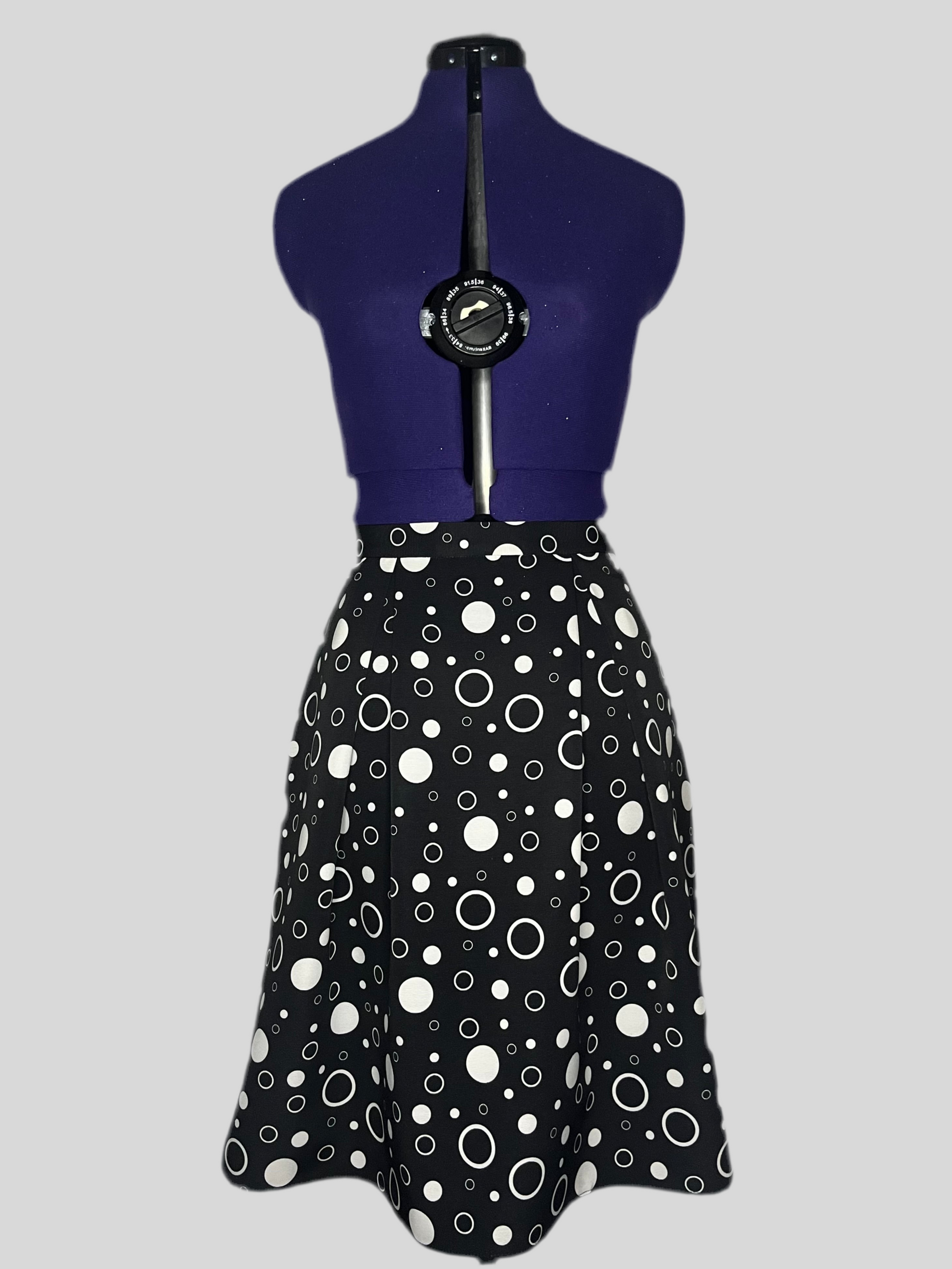Mannequin wearing a black and white pleated skirt with polka dot pattern.