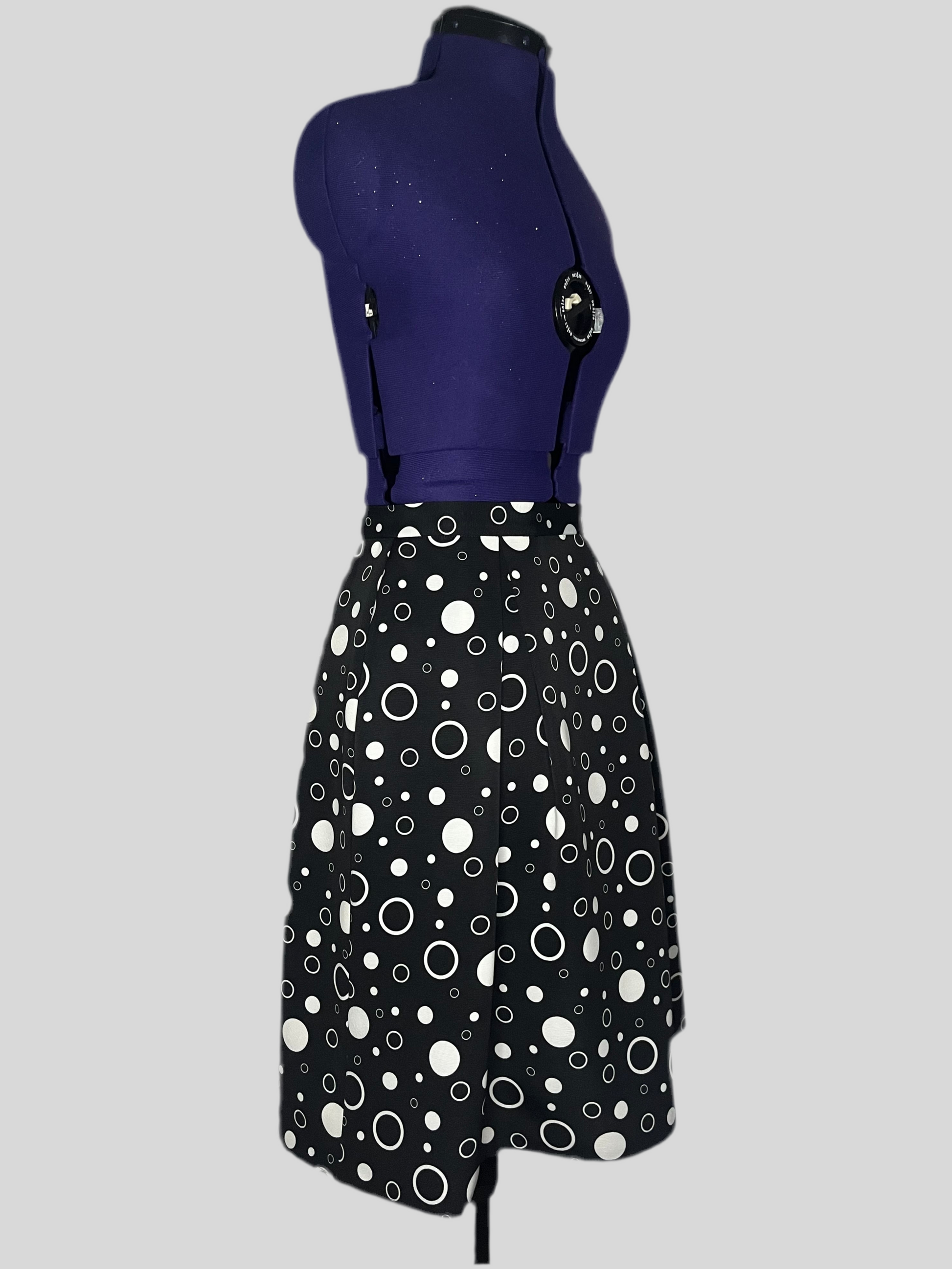 Mannequin wearing a black and white pleated skirt with polka dot pattern.