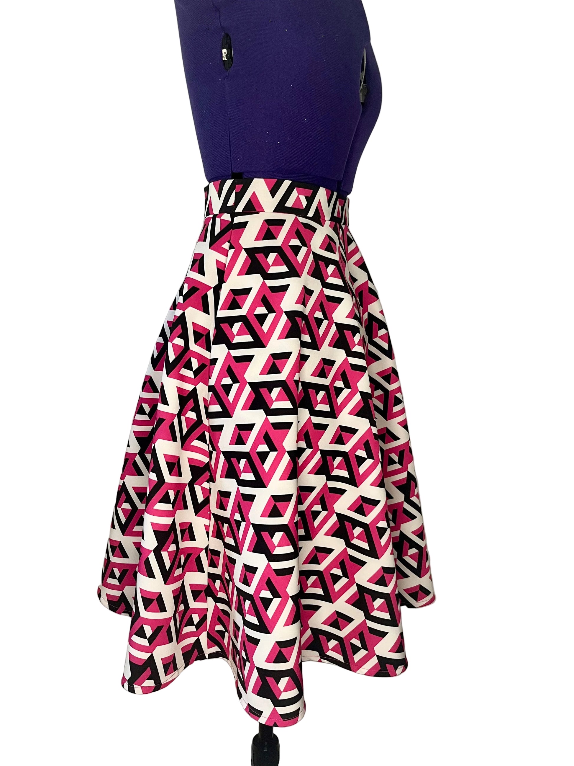 Half-circle skirt with geometric white, black and fuchsia pattern on a mannequin, featuring inseam side pockets.