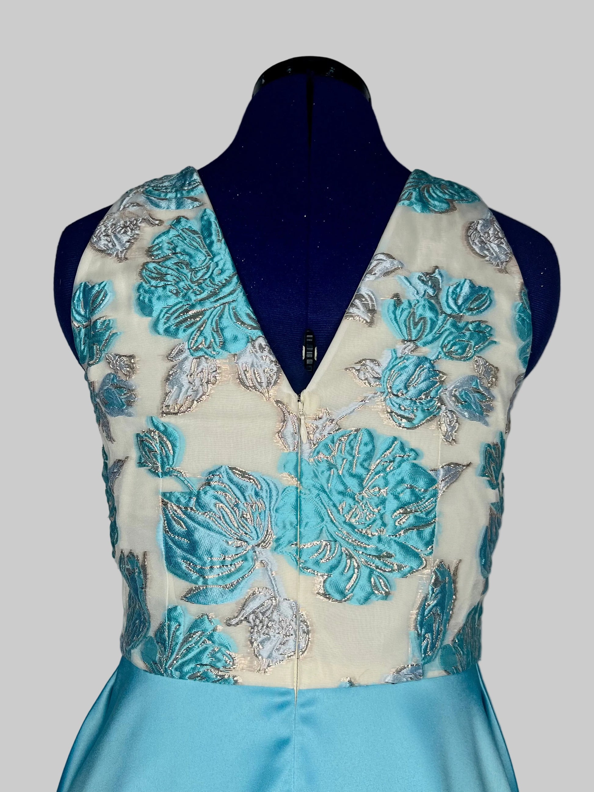 Mannequin wearing a blue and beige floral embroidered dress with a plain background