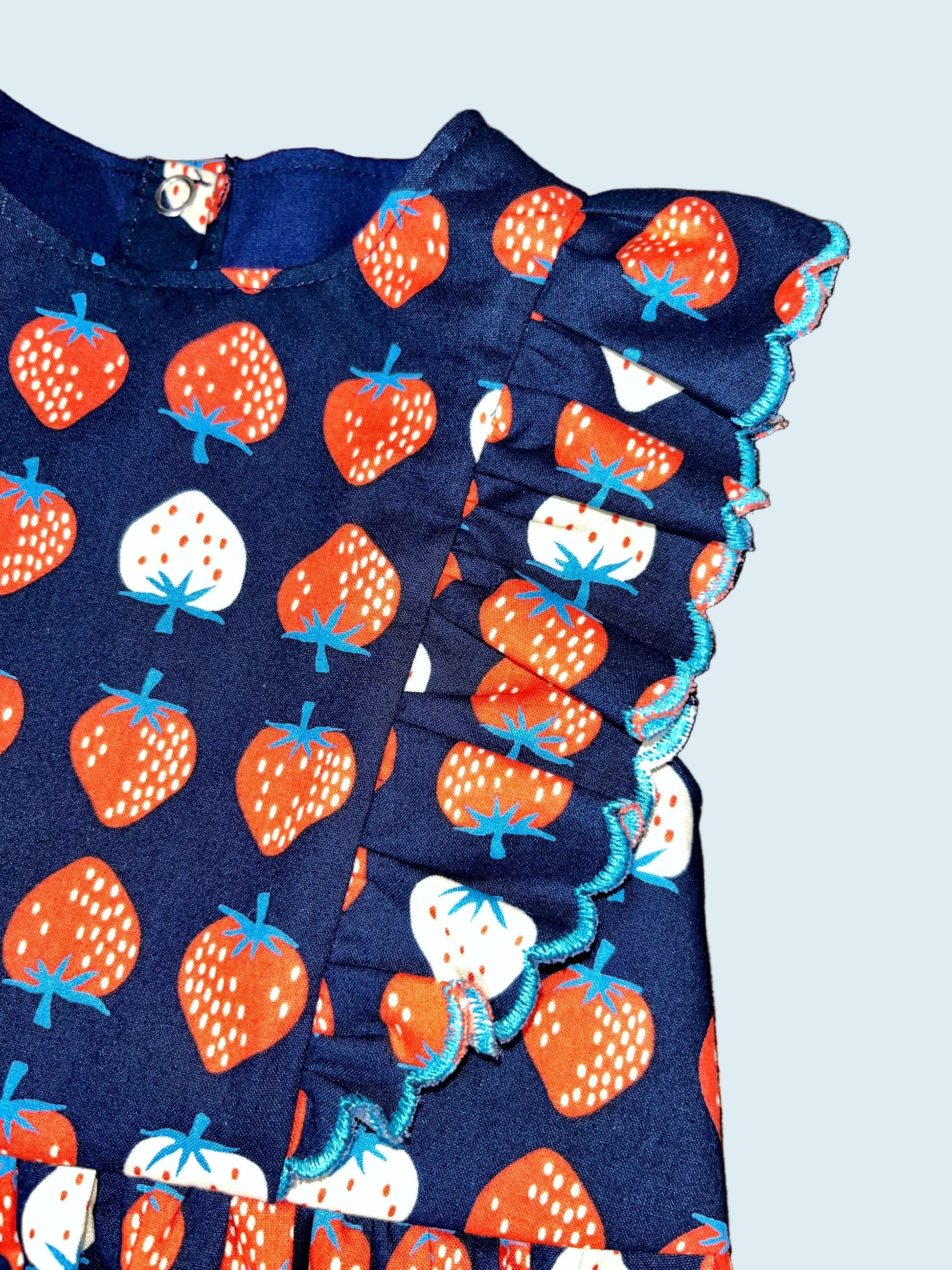 Navy blue fabric with red and white strawberry pattern. Ruffle detail. 
