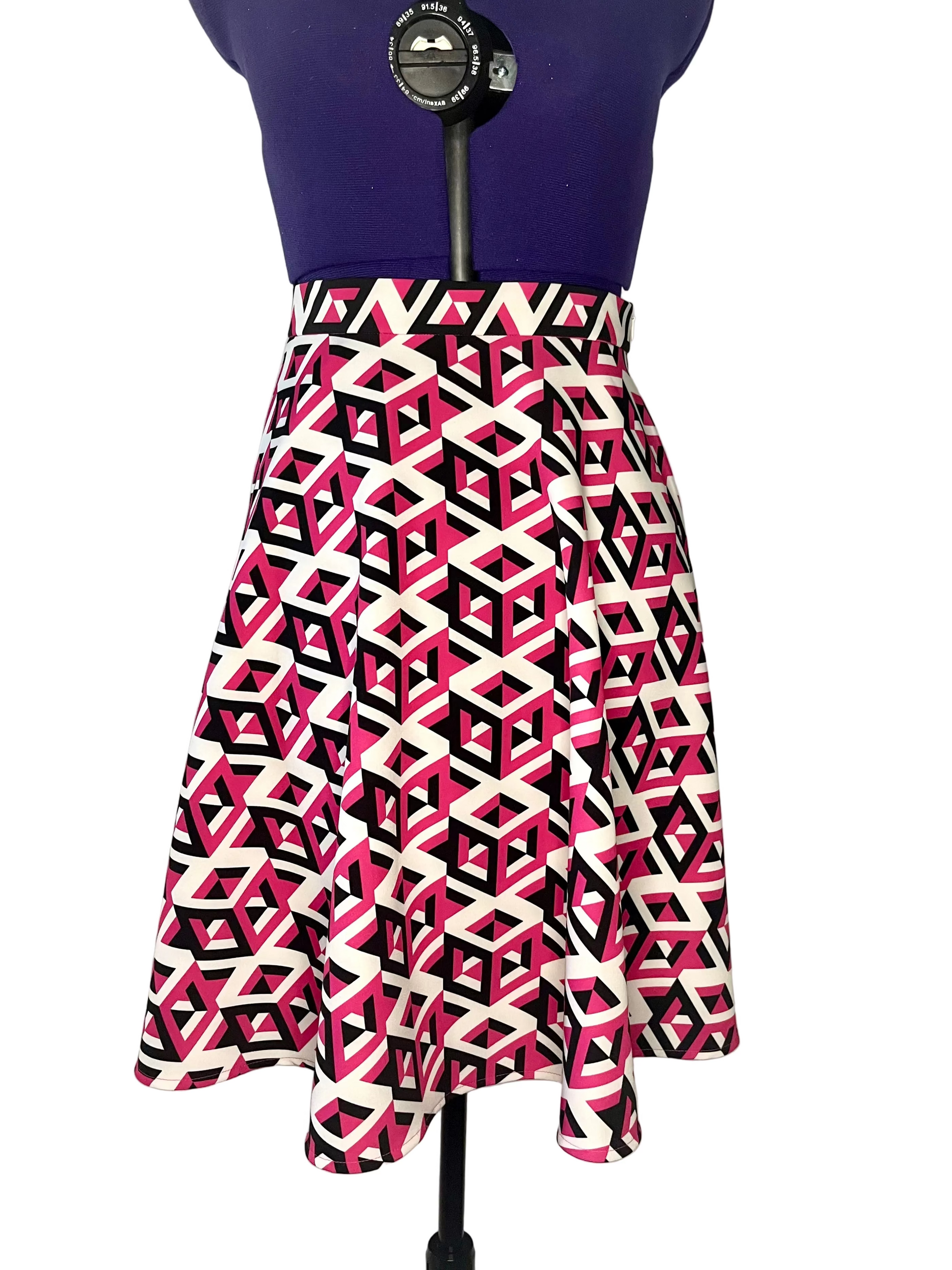 Half-circle skirt with geometric white, black and fuchsia pattern on a mannequin, featuring inseam side pockets.