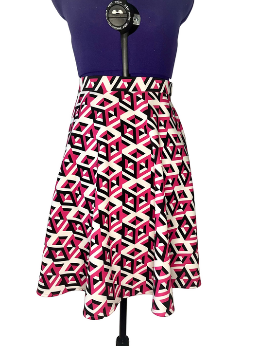 Half-circle skirt with geometric white, black and fuchsia pattern on a mannequin, featuring inseam side pockets.