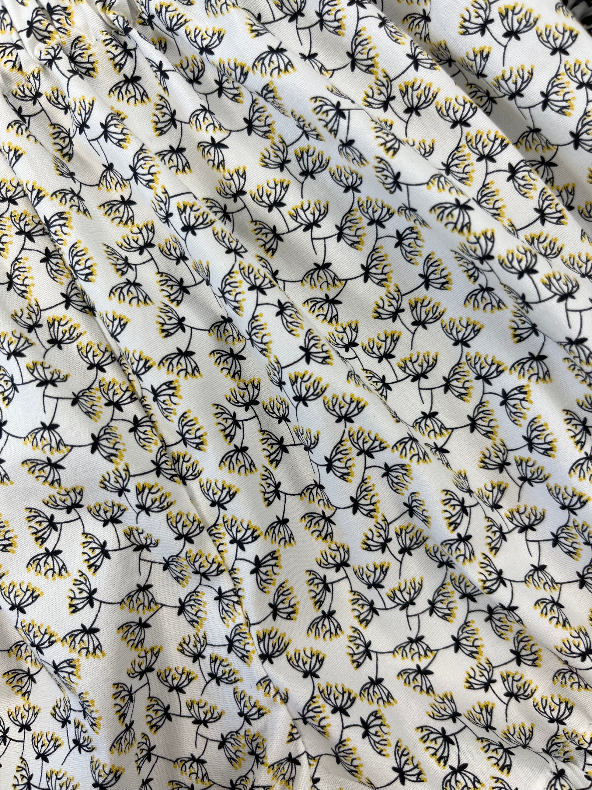 Fabric with a pattern made of small black and yellow dandelion