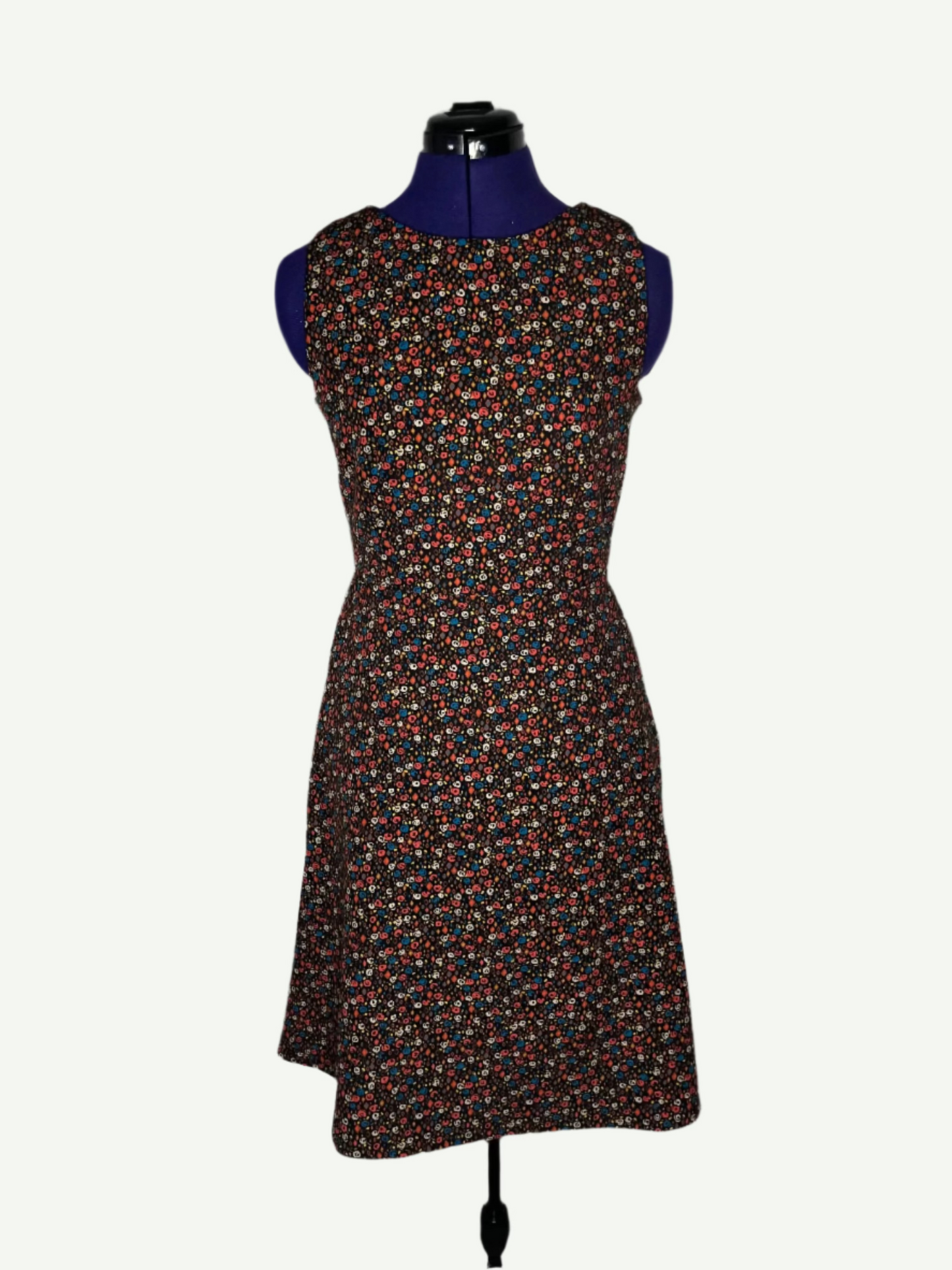Multicolored patterned dress on a mannequin. It features a fitted bodice and a flared skirt with pockets.
