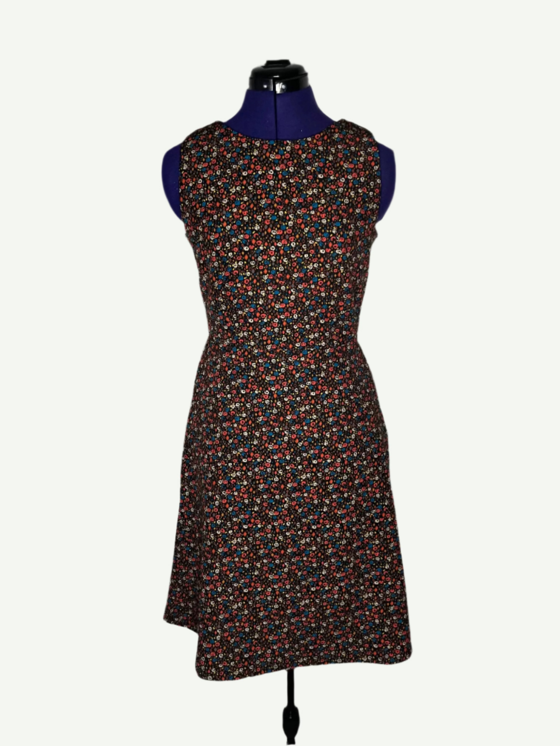 Multicolored patterned dress on a mannequin. It features a fitted bodice and a flared skirt with pockets.