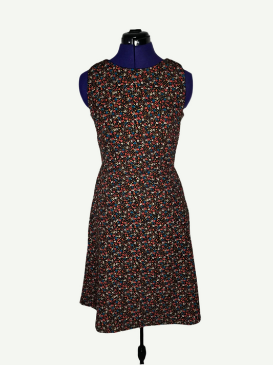 Multicolored patterned dress on a mannequin. It features a fitted bodice and a flared skirt with pockets.