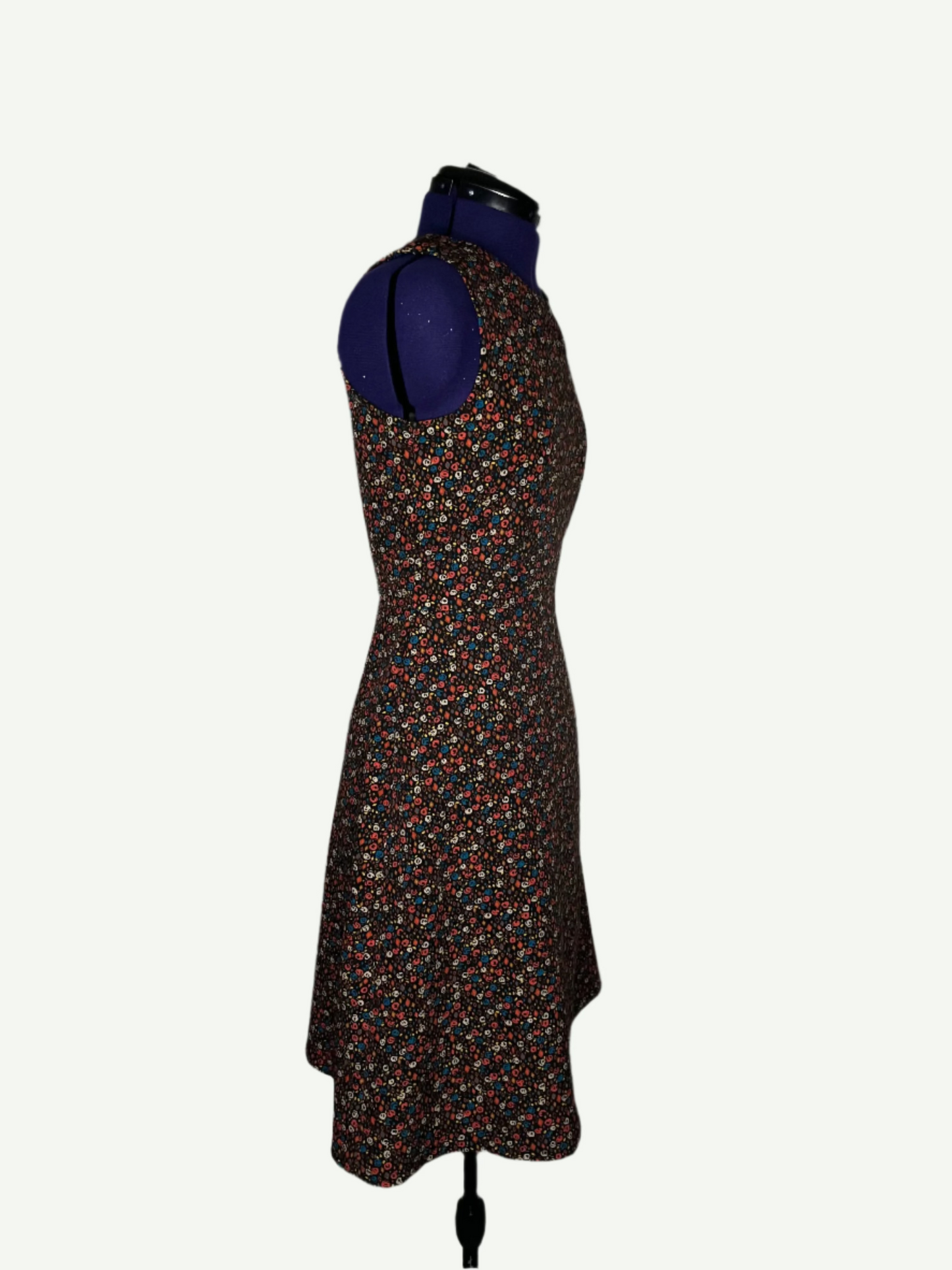 Multicolored patterned dress on a mannequin. It features a fitted bodice and a flared skirt with pockets.