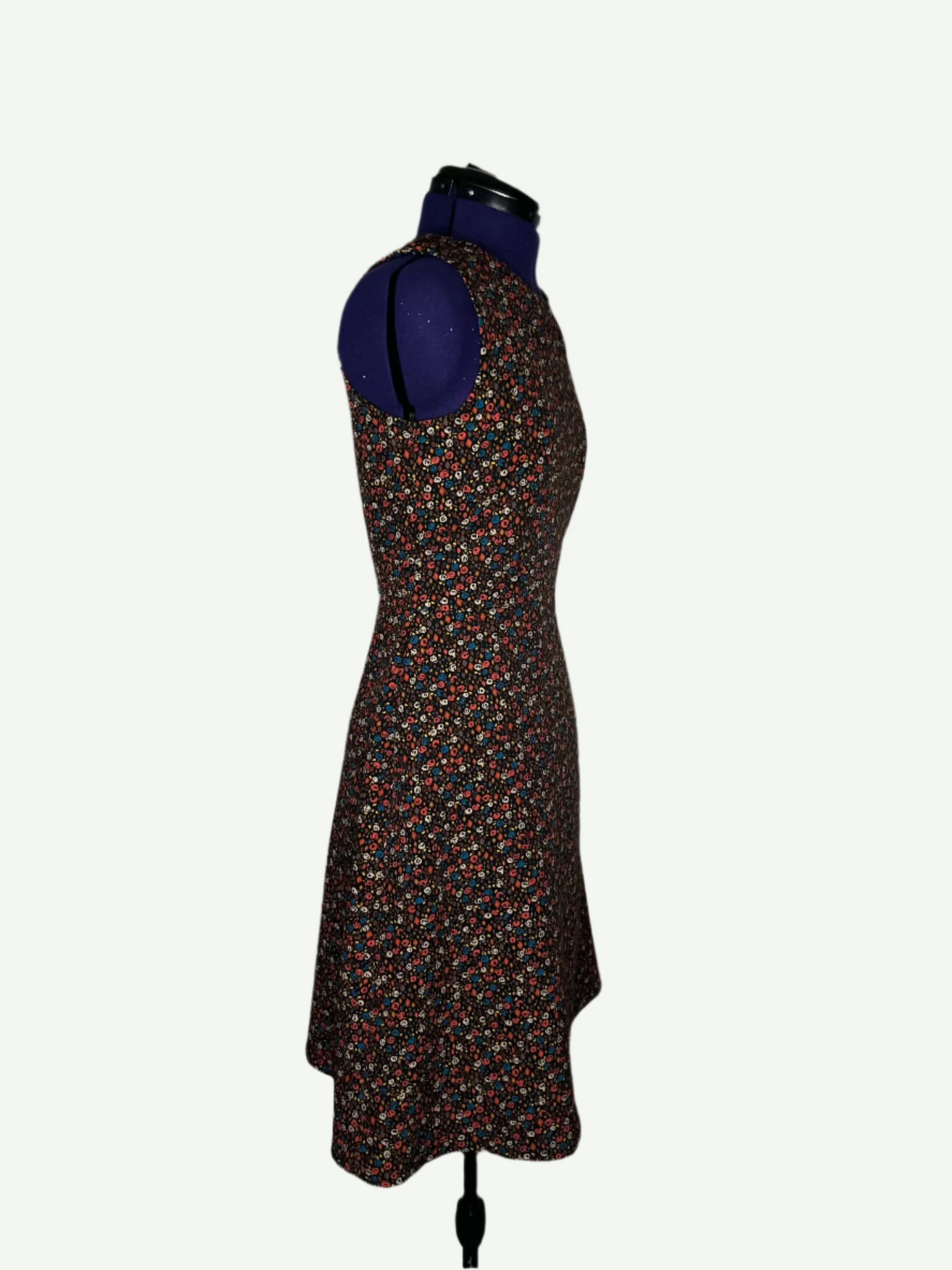 Multicolored patterned dress on a mannequin. It features a fitted bodice and a flared skirt with pockets.