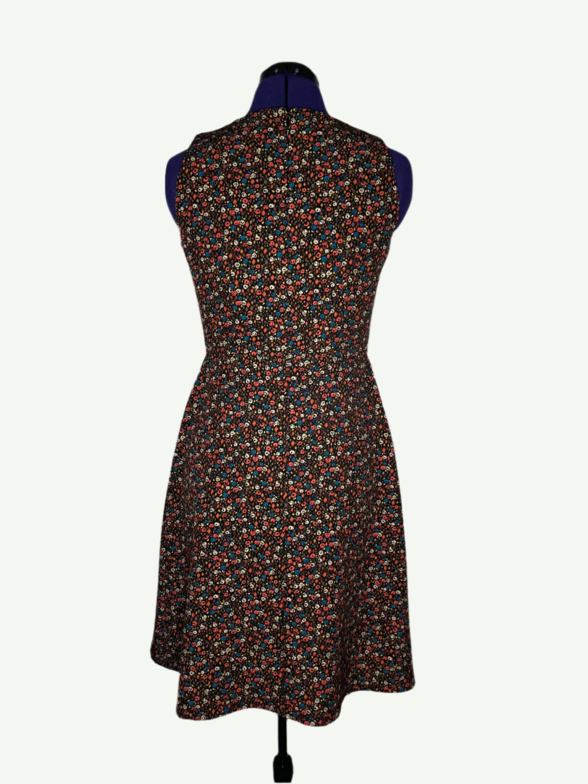 Multicolored patterned dress on a mannequin. It features a fitted bodice and a flared skirt with pockets.