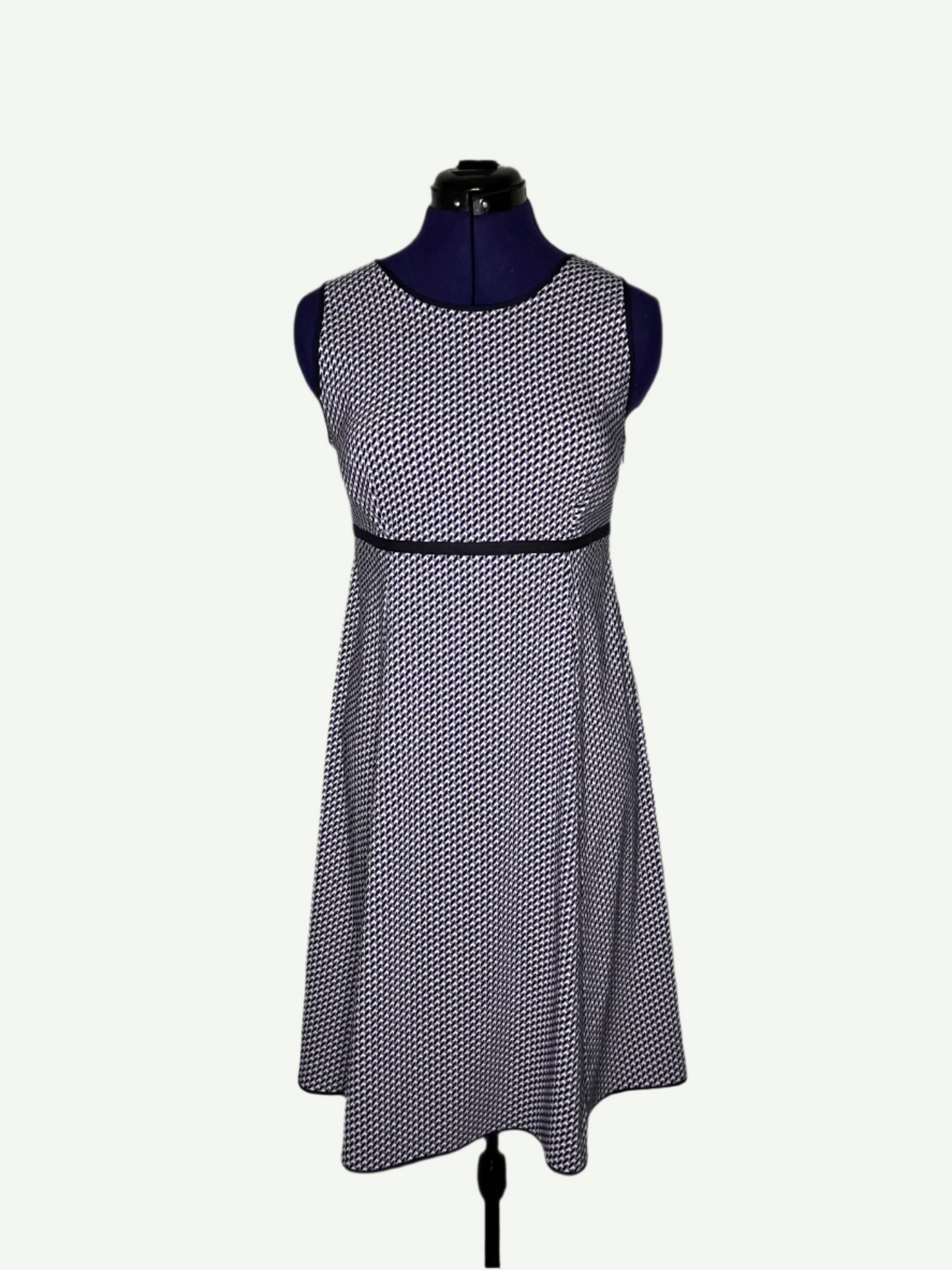 White, purple and navy patterned dress on a mannequin, featuring a round neckline and an empire-style design.