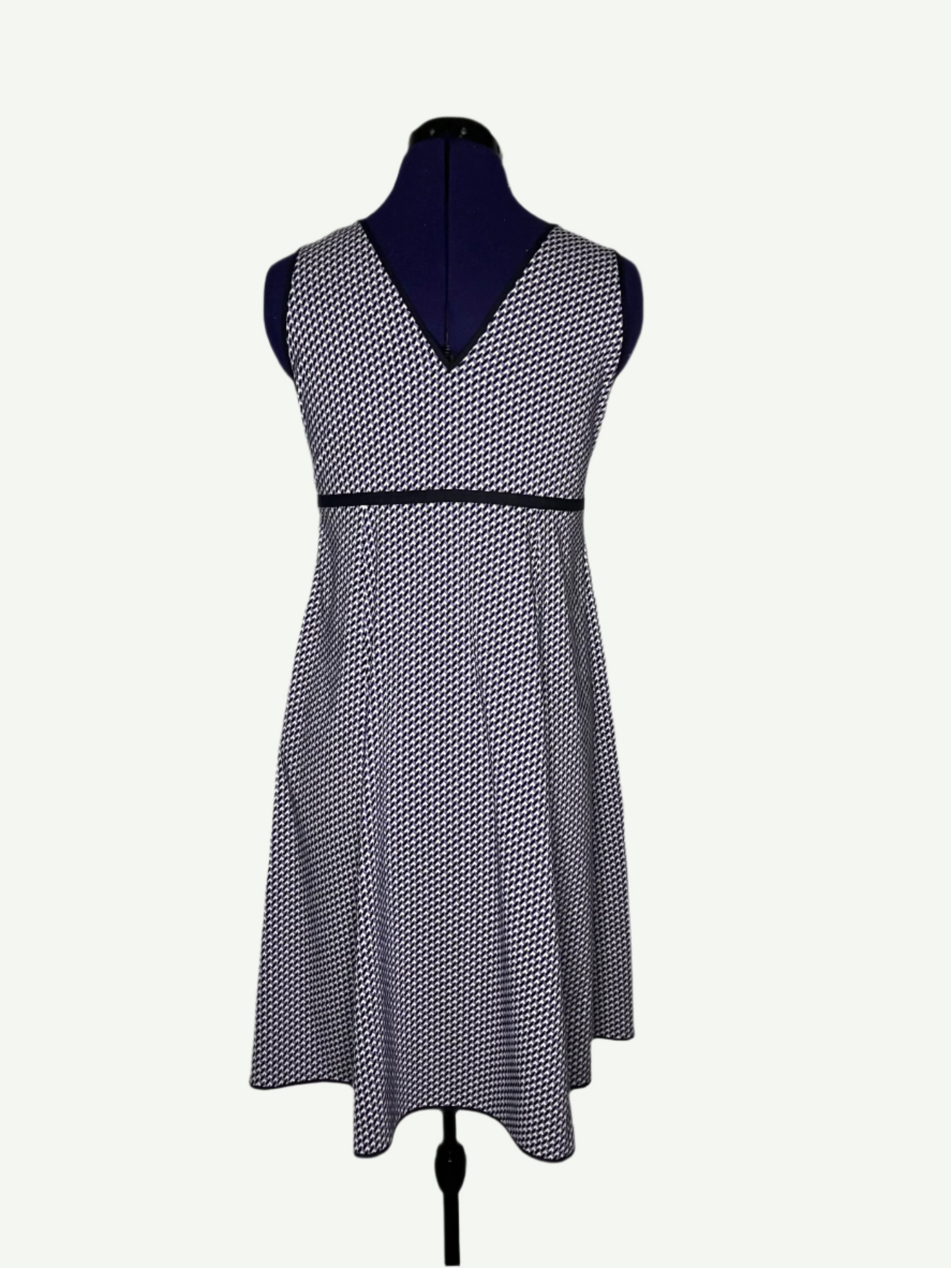 White, purple and navy patterned dress on a mannequin, featuring a round neckline and an empire-style design.